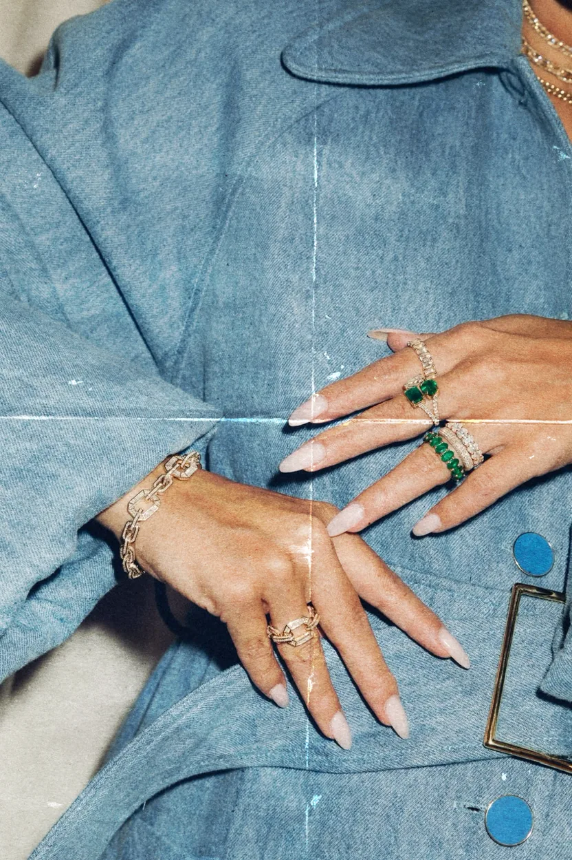 Hands wearing colorful rings against blue denim